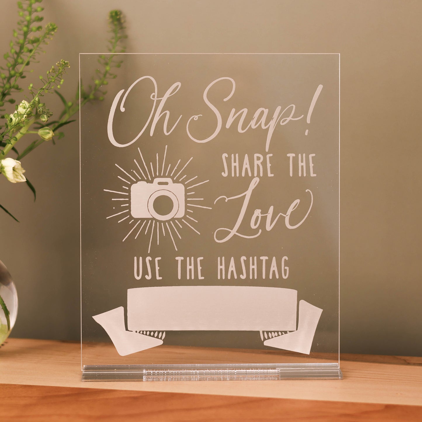 Clear acrylic tabletop sign engraved with the words 'Oh Snap, Share the Love' and a white blank spot where you can write in your personal hashtag with dry erase or permanent marker.   