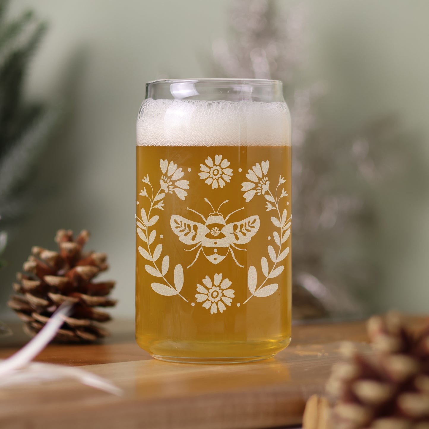 16 oz can glass filled with beer with Scandinavian design featuring a bee and florals