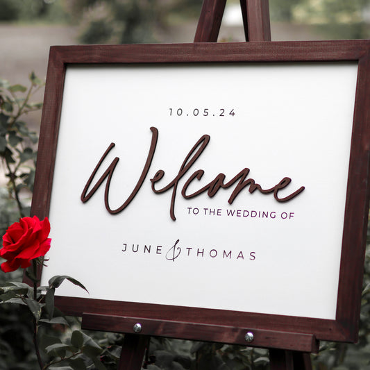 Personalized wedding sign with white background, wood cutout letters, and mahogany frame. Names of bride and groom, plus wedding date place in a backyard setting.