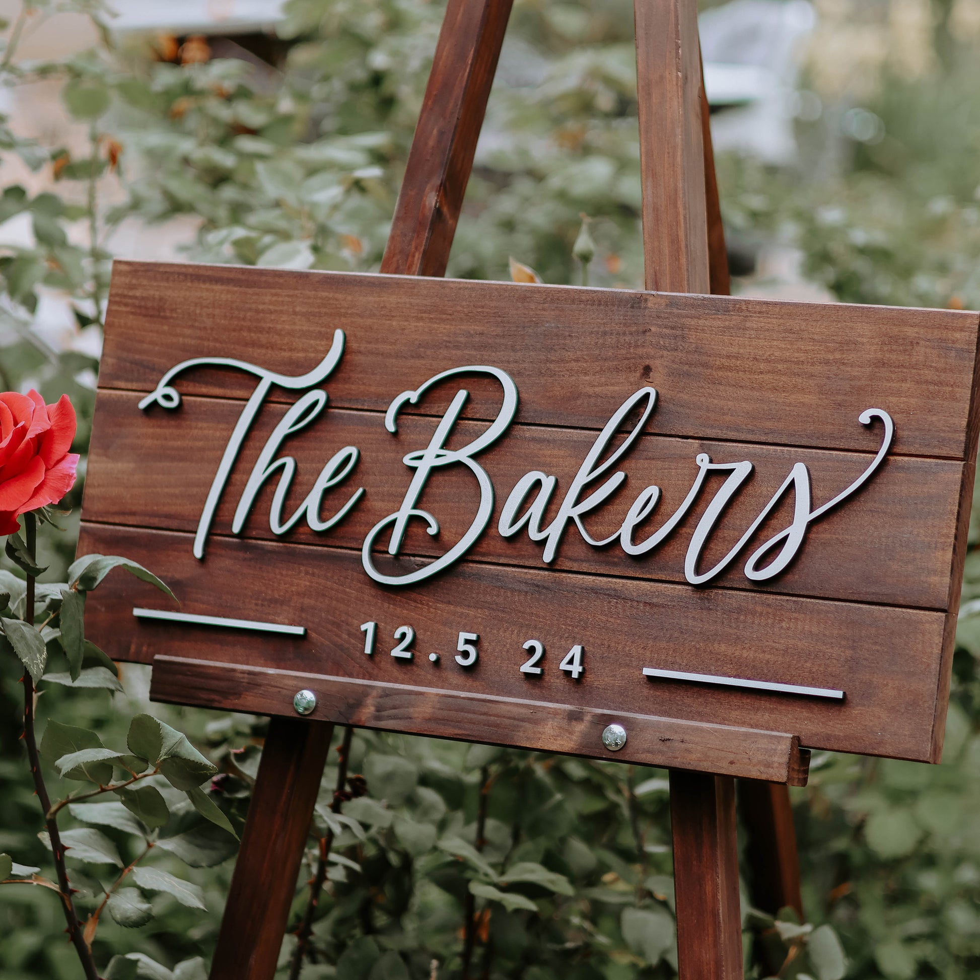 Wedding last name sign with Mahogany stain and white relief letters in a garden. 